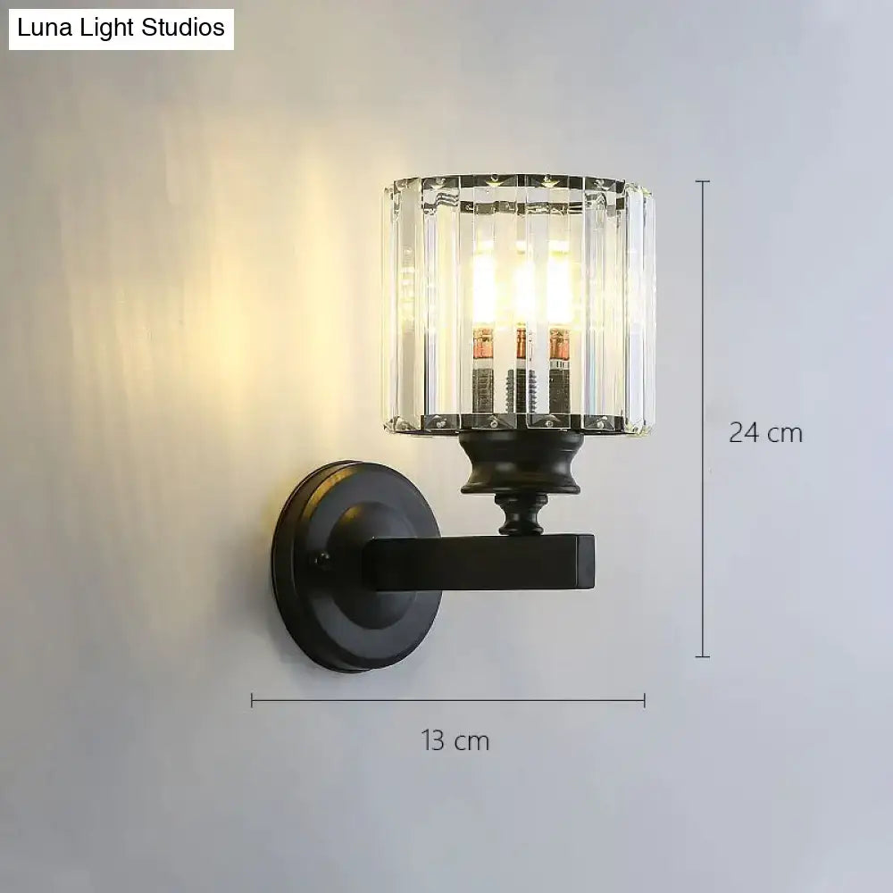 Black wrought iron modern minimalist wall sconce with cylindrical crystal glass shade for bedroom lighting
