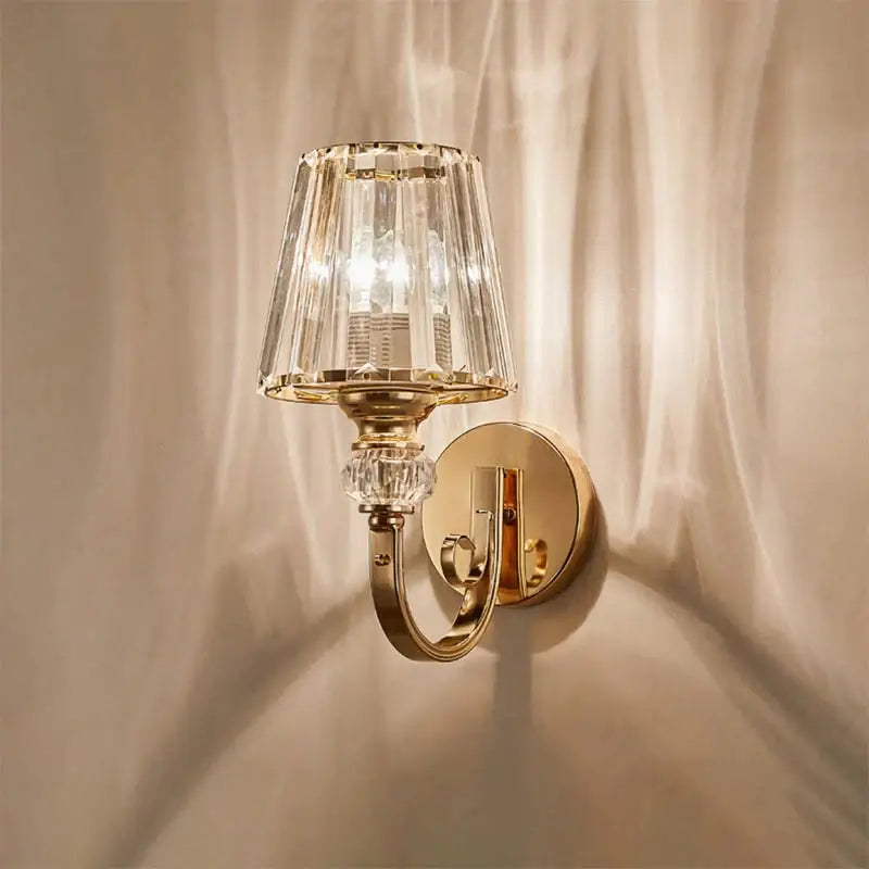 Modern minimalist gold wall lamp featuring a gold-toned wall sconce with faceted crystal shade and decorative accents