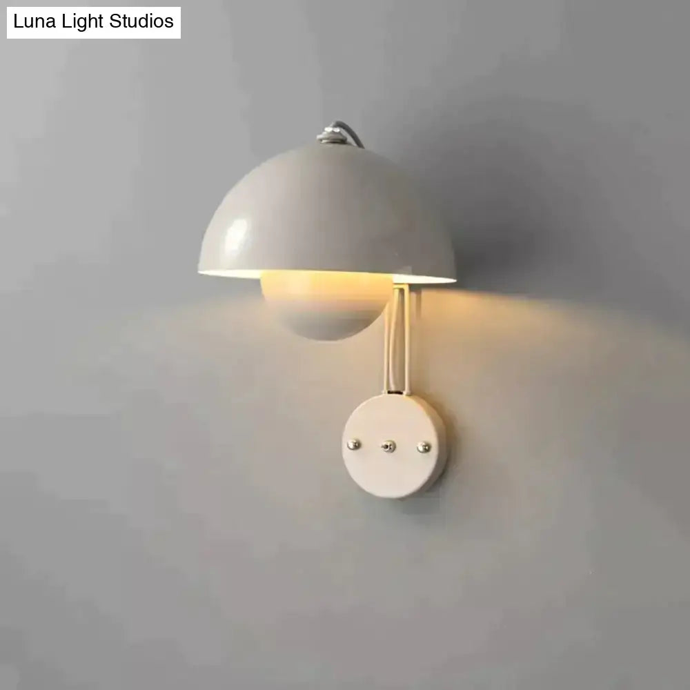 A sleek white ceramic wall lamp with dome-shaped shade and brass base type finish for modern bedroom decor