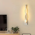 Modern white geometric wall lamp with twisted design emitting warm light for stairway illumination