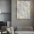 Modern white geometric wall lamp with illuminated recessed panels creating a three-dimensional angular pattern