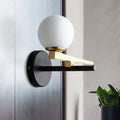 Modern white glass sphere wall light with gold accents and black base single light for bedroom use