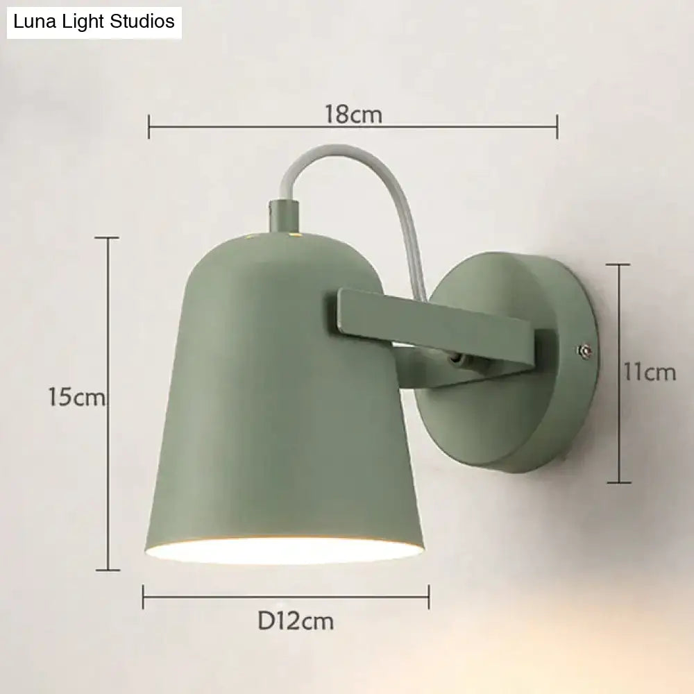 A sleek matte sage green ferrell wall lamp with curved arm and circular base for modern bedroom spotlight