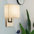 Modernist gold and beige sconce light fixture with gold-toned rectangular base and beige fabric shade for bedroom wall use