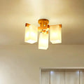 Nordic wood ceiling lamp with warm-toned finish and three cuboid cream glass shades for living room lighting