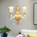 Ornate gold floral wall lamp with two frosted glass tulip shades and clear crystal glass teardrop accents for bedroom use