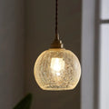 A warm glowing decorbites pauline modern industrial ceiling light with crackled clear glass and brass hardware