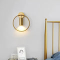 Postmodern gold-toned circular wall sconce with minimalist cylindrical light fixture and 16 inches fixture height for bedroom