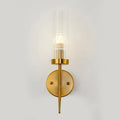 Postmodern gold-toned wall sconce with clear ribbed glass cylinder and slender metallic stem for stairway lighting