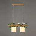 Decorbites modern wood linear island lighting with warm cylindrical shades and maple leaf plant accents on natural wood branch