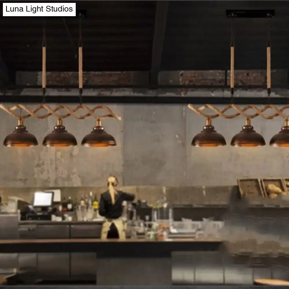 Industrial-style kitchen pendant lights with bronze metal shades and twisted copper suspension rods hanging from a rustic wooden beam