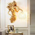 Sculptural gold wall lamp featuring a violin-playing female figure with an ornate crystal wall lamp globe shade