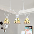 White wrought iron pendant light with three stained glass shades featuring yellow green leaf pattern and stainless glass cones