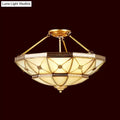 Gold-toned semi-flush mount fixture with geometric stained glass and brass accents 23.5 to 32 inch width 220v-240v
