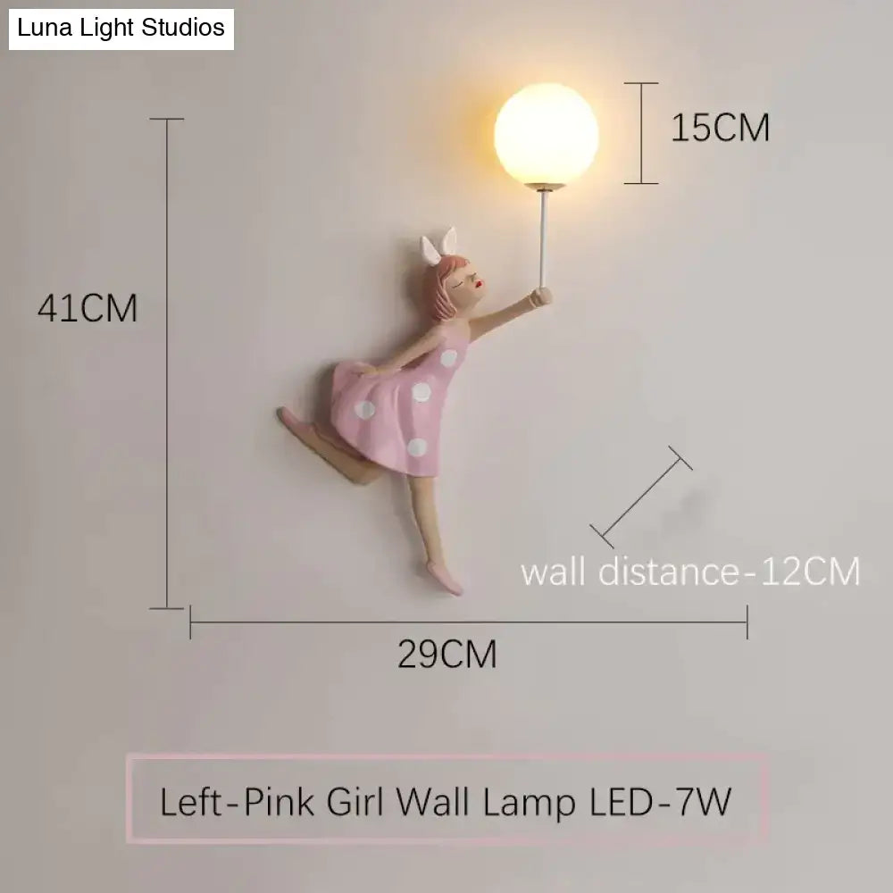 Whimsical pink polka dot girl wall lamp featuring a dancing figure holding an illuminated globe bulb for bedroom use