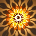 A warm glowing wooden floral sunburst wall lamp with orange and yellow leaf-shaped panels for bedroom lighting